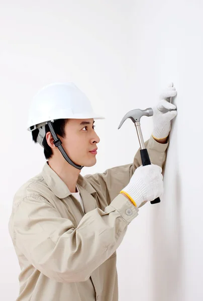 worker in helmet and gloves holding a drill on white background