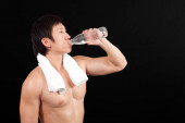 mladý muž pití vody z láhve izolované na černé