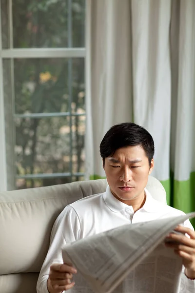 portrait of a mature asian man reading a newspaper
