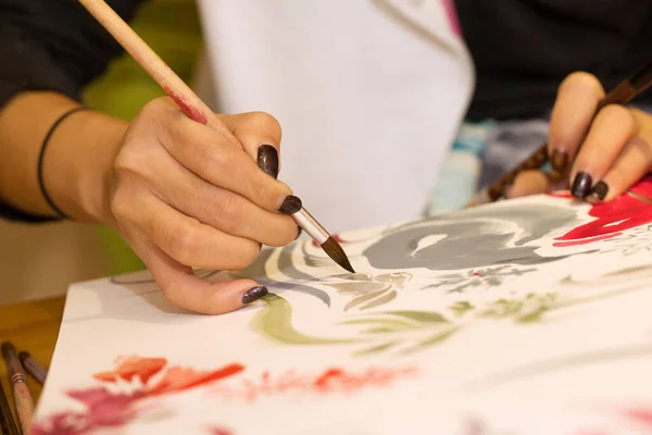 artist drawing on a white paper with a brush