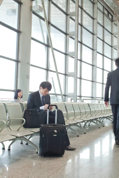 young man sitting in airport with luggage and looking away