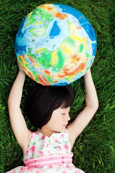 little girl with a globe in the grass