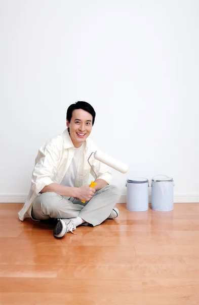 young woman sitting on floor with paint roller