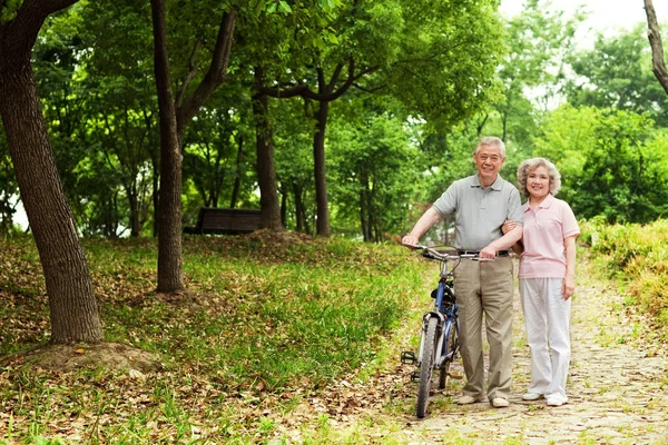 senior couple with bicycle in park