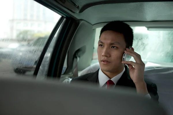 young businessman driving car with mobile phone