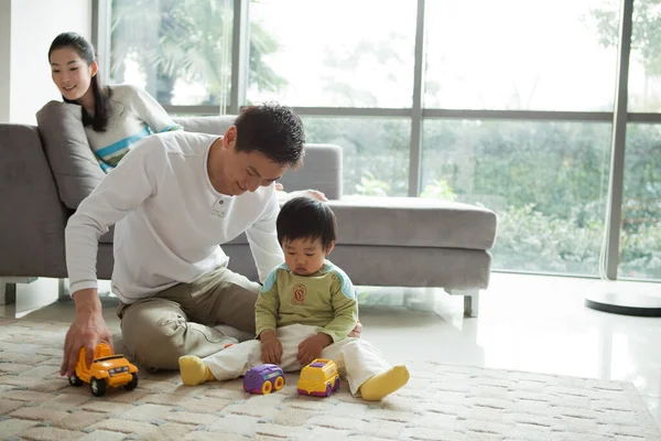 father and son playing with toy car at home