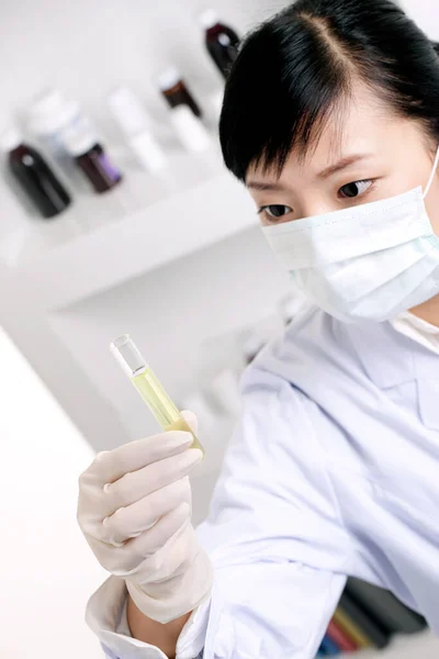 young female scientist in lab coat with test tube and flask in laboratory