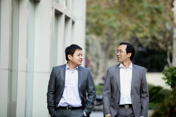 business people, partnership and teamwork concept-happy couple with two businessmen standing in front of office building