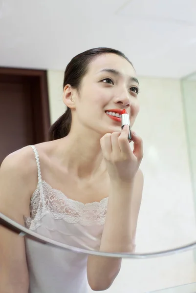 young woman applying makeup on her face