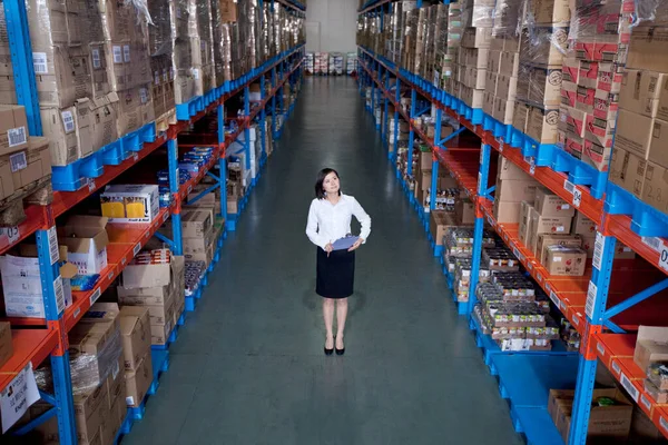 young woman in a warehouse with a large stack of goods
