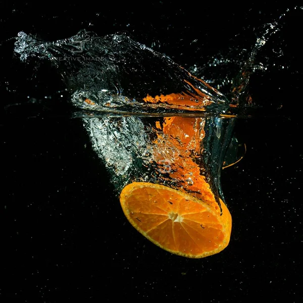 orange juice with water splashes on black background