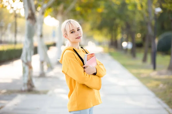 young woman with backpack and notebook on the street