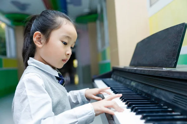 little girl playing piano with a toy