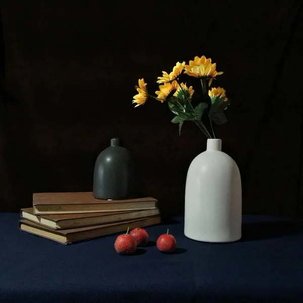 still life with a bouquet of flowers and a book on a dark background