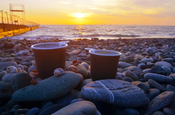 two cups of coffee at sunset by the sea