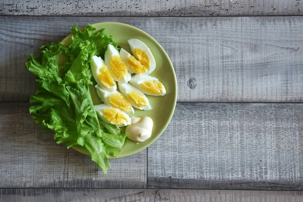 Φέτες Βραστών Αυγών Πιάτα Διακοσμημένο Ένα Φύλλο Πράσινου Μαρουλιού Ξύλινο — Φωτογραφία Αρχείου