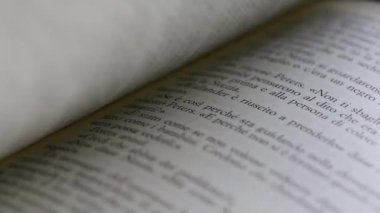 Bir adamın elinin makrosu bir kitabın sayfalarını çeviriyor.