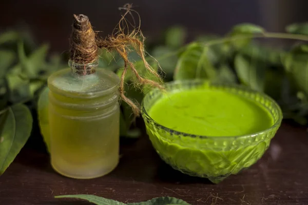 All scalp related problems solution lotion or shampoo in a glass bowl consisting of some neem  leaves, fenugreek seeds and olive oil. Shot of fresh leaves of Neem tree, fenugreek seeds, pack,& olive oil.