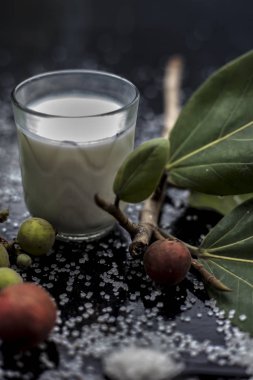 Banyan Ağacı meyve suyu, süt ve biraz şekerle karıştırılmış siyah parlak ahşap yüzeydeki ağırlığı kontrol etmek için en iyi içecek ilacı. Tüm malzemeler yüzeyde. Dikey çekim..