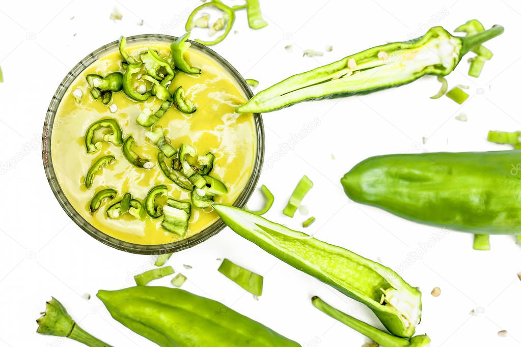 Raw cut green chili isolated on the white surface along with its tangy spicy green chili sauce in a glass bowl. Horizontal top shot.