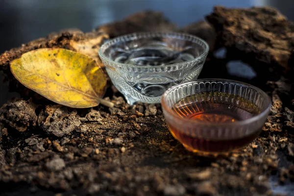 Home remedy for sexually transmitted diseases on a black glossy surface consisting of Banyan tree bark powder well mixed with water and some honey. Horizontal high angle shot.