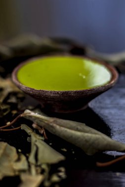 Kurumuş yaprak tozu ya da Banyan ağaç yapraklarıyla birlikte siyah parlak bir yüzey üzerinde bir kil kasede Banyan ağaç macununu yakın plan çek. Banyan ağaç yaprağının öğütülmüş tozu bir kasede suyla karıştırılmış..