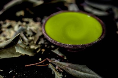 Kurumuş yaprak tozu ya da Banyan ağaç yapraklarıyla birlikte siyah parlak bir yüzey üzerinde bir kil kasede Banyan ağaç macununu yakın plan çek. Banyan ağaç yaprağının öğütülmüş tozu bir kasede suyla karıştırılmış..