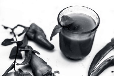 Sıcak, baharatlı, keskin ve izole edilmiş bir bardakta yeşil biber suyu. Yatay olarak kesilmiş taze çiğ biber ve beyaz bir yüzeyde cam bir kasede meyve suyu. Maske kırpma..