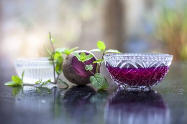 Tahta yüzeyde kepek için ev yapımı ilaç yani cam bir kâsede suyla karıştırılmış pancar kökü ve biraz da taze pancar. Bulanık kremalı Bokeh ile yatay çekim.
