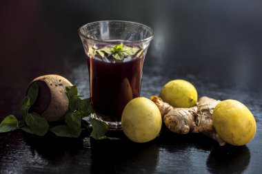 Beetroot juice with some mint leaves lemon juice and ginger in it on black glossy surface in a glass for weight loss. Horizontal shot with bokeh background. clipart