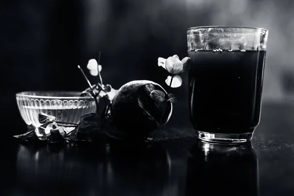 Beetroot smoothie in a glass on black glossy surface with some fresh mint leaves and water.Horizontal shot of beetroot smoothie along with some mint leaves. Shot with blurred background.