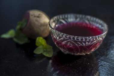 Böbrek iltihabına çare olarak kullanılan çiğ taze pancar pancarı sebzesiyle siyah parlak bir yüzey üzerinde cam bir kasede çıkarılmış pancar tentürü. Yatay çekim.
