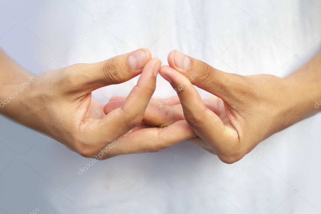 Isolated hands of teenage boy doing Mida-no Jouin Yoga Mudra on a white background by interlacing his fingers and joining the first finger with the thumb.