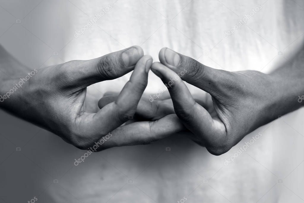 Isolated hands of teenage boy doing Mida-no Jouin Yoga Mudra on a white background by interlacing his fingers and joining the first finger with the thumb.