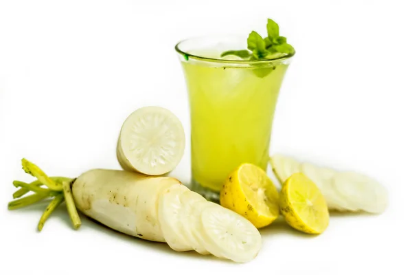 白を基調としたグラスに新鮮な大根ジュースのショットを閉じ いくつかのスライスされた大根とレモンを入れます 水平な大根汁にミントの葉が付いています — ストック写真