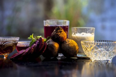 Siyah parlak bir yüzey üzerine pancar maskesi. Süt ve bal ile karıştırılmış pancar suyu içeriyor. Kuru cilt için spa 'da kullanılır. Ahşap bir yüzey üzerinde pancar maskesi yatay görüntüsü.