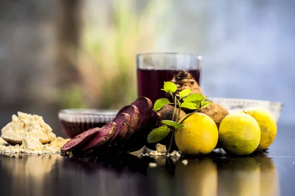 Face mask for a natural glow for all skin types on the black wooden surface consisting of some beetroot juice, yogurt, lime juice, and gram flour. Shot of face mask with entire ingredients.Horizontal shot.