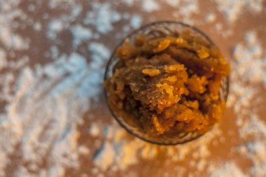 Hint Gujarati 'sinin popüler yemeği Atte ka sheera ya da Halwa-Karah parshad' ı kahverengi bir yüzeye serpiştirilmiş buğday unuyla birlikte cam bir kaseye koy. Yatay üstten çekim.