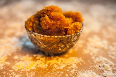 Hint Gujarati 'sinin popüler yemeği Atte ka sheera ya da Halwa-Karah parshad' ı kahverengi yüzey üzerinde bir cam kasede biraz buğday unuyla kaplayın. Yatay çekim.