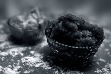 Hint Gujarati 'sinin popüler yemeği Atte ka sheera ya da Halwa-Karah parshad' ı kahverengi bir yüzeye serpiştirilmiş buğday unu ve cam bir kase içindeki jaggery ile yakın çekim yapın. Yatay çekim.