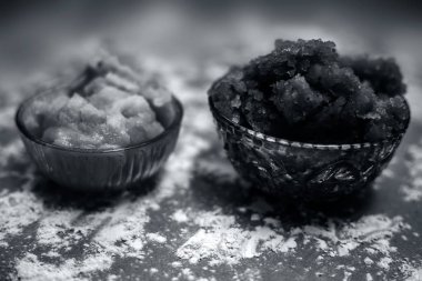 Hint Gujarati 'sinin popüler yemeği Atte ka sheera ya da Halwa-Karah parshad' ı kahverengi bir yüzeye serpiştirilmiş buğday unu ve cam bir kase içindeki jaggery ile yakın çekim yapın. Yatay çekim.