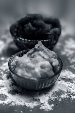 Hint Gujarati 'sinin popüler yemeği Atte ka sheera ya da Halwa-Karah parshad' ı kahverengi bir yüzeye serpiştirilmiş buğday unu ve cam bir kase içindeki jaggery ile yakın çekim yapın. Dikey çekim.