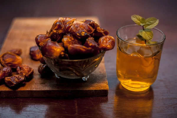 Close up of raw dates along with its syrup in a glass with some mint leaves on it which helps in weight loss, constipation aid and promotes heart health. Horizontal shot.