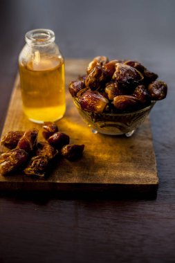Bardakta şerbet, çiğ kurutulmuş hurma ve ahşap bir yüzeyde cam bir şişede pişirme yağı. Çiğ tarihli dikey hurma şurubu ve pişirme yağı..