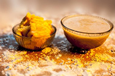 Close up of Indian desi winter drink Bajri Rabb winter drink or Bajri ki rabdi/rabri in a glass bowl along with some raw spread pearl millet flour and jaggery. On a  brown wooden surface. clipart