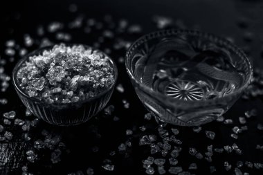 Gond katara / Gond Katira / Tragacanth Gum veya cam bir kasede yenebilir sakız ve sırt ağrısı için başka bir kasede biraz su. Siyah parlak bir yüzey üzerinde, yayılmış gond kristalleri ile..