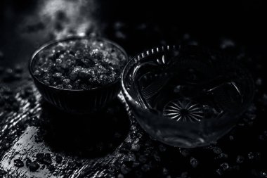 Gond katara / Gond Katira / Tragacanth Gum veya cam bir kasede yenebilir sakız ve sırt ağrısı için başka bir kasede biraz su. Siyah parlak bir yüzey üzerinde, yayılmış gond kristalleri ile..
