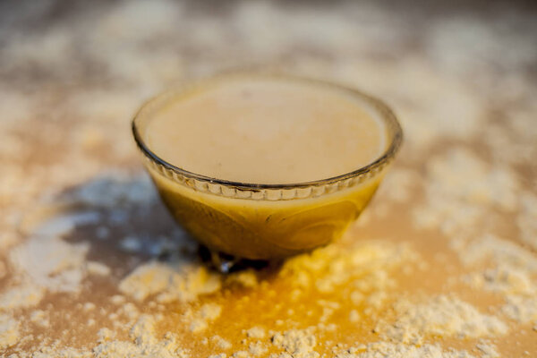 Закройте индийский деси зимний напиток Bajri Rabb зимний напиток или Bajri ki Rabdi / Rabri в стеклянную миску вместе с сырой распределенной жемчужной просо муки и jaggery. На коричневой деревянной поверхности
.