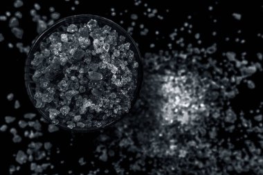 Gond / Goond / yenilebilir sakız kristallerini siyah parlak bir yüzey üzerinde şeffaf cam bir kâse içinde biraz yayılmış olarak yakın çekim yap. Yenebilir sakız ya da cam bir kasede Tragancath. Yatay üst çekim..