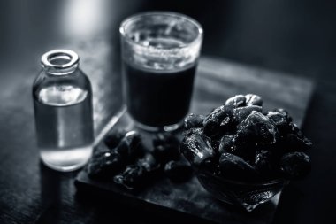 Bardakta şerbet, çiğ kurutulmuş hurma ve ahşap bir yüzeyde cam bir şişede pişirme yağı. Çiğ tarihli yatay hurma şurubu ve pişirme yağı..